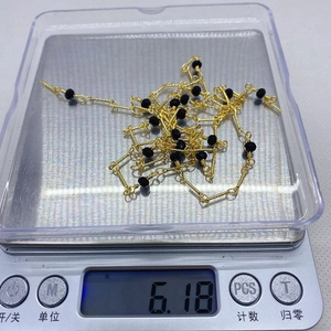 Detalle macro que muestra un peso de 6,18 g de cadena dorada con cuentas de cristal