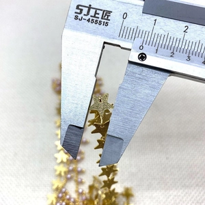 Detalle de la medición de un colgante de estrella dorada con un calibre digital