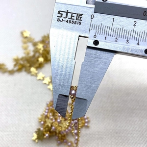 Detalle de cadena con perlas rosa de 4mm y dijes de estrella dorada para joyería