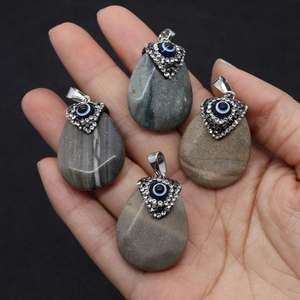 Detail view of water-drop natural agate pendants with evil eye inlay and silver bails