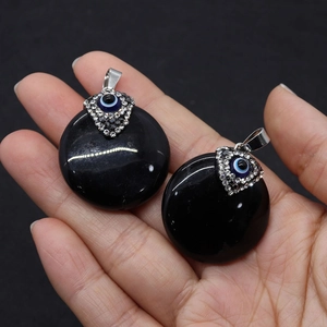 Detail of hand-held black agate pendants with evil eye rhinestone encrusted metal clasps