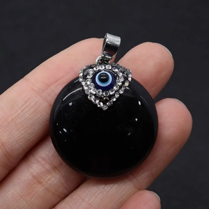 Detail of black onyx stone pendant with evil eye heart motif held in hand