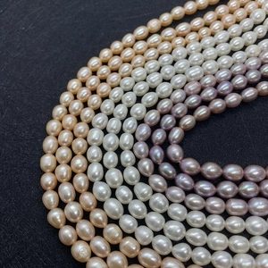 Détail de perles d'eau douce ovales en blanc rose et violet sur fond sombre
