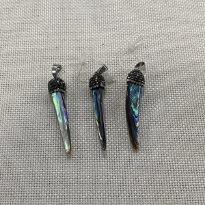 Makro-Detail von natürlichen Abalone-Muschel-Anhängern mit funkelnden Strass-Kappen-Details