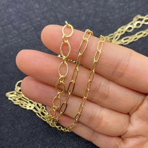 Close-up of assorted gold-plated oval link and paperclip chains held by a hand