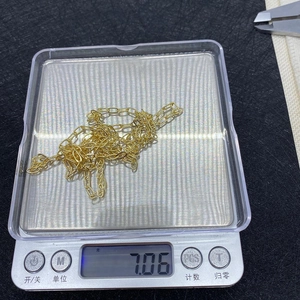 Detail shot of a 7.06g gold oval link chain being weighed on a digital scale