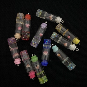 Macro shot of 11x41mm glass cylinder pendants with dried flowers and colored resin caps