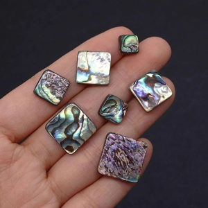 Macro detail of natural abalone shell square beads with iridescent luster on hand