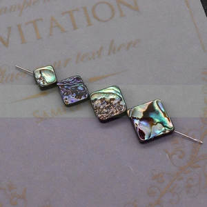 Macro detail of natural abalone shell square beads showing iridescent rainbow luster