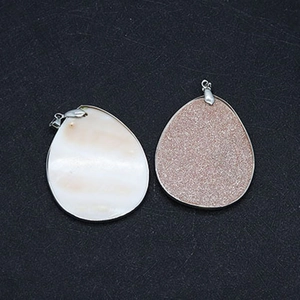 Detail of drop-shaped shell and goldstone pendants with polished silver metal edging