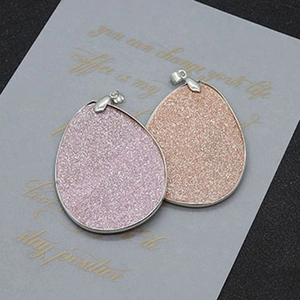 Detailed macro view of pear-shaped frosted shell pendants with silver metal frames