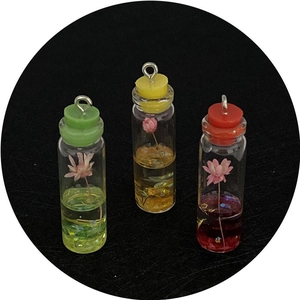 Three assorted cylinder glass flower pendants with colorful caps and metal hanging loops