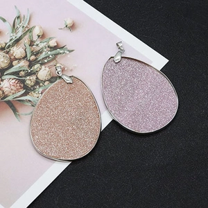 Detailed macro view of teardrop natural shell pendants with glittering gold and purple finish