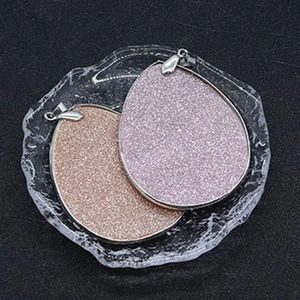 Macro view of teardrop natural shell pendants with glitter texture in a glass dish
