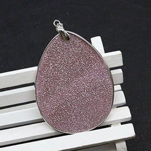 Macro detail of large teardrop shell pendant with pink glitter and silver metal frame