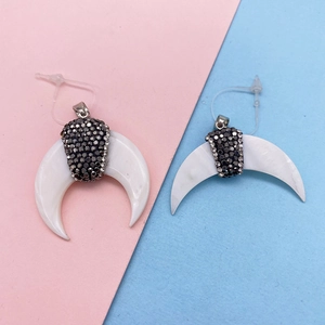 Dettaglio di pendenti a mezzaluna in conchiglia naturale con inserto in strass lucido