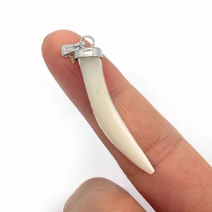 Macro shot of a cream-white shell pepper pendant held by hand to show its 37mm size scale
