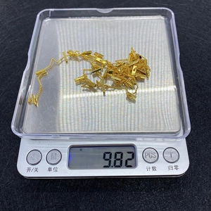 Detailed view of golden twisted rectangular chain links being weighed on a digital scale
