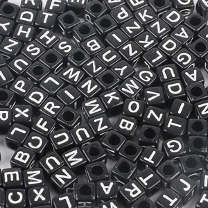 Macro view of black acrylic cube beads with white capital letters for DIY jewelry