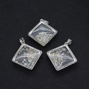 Three diamond-shaped silver pendants with white crystal fragments on a black background