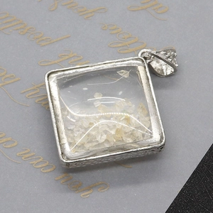 Close-up of diamond-shaped white crystal stone pendant with engraved silver bail