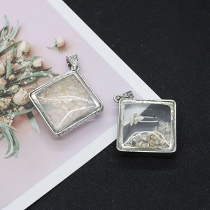 Detail view of square glass pendants with yellow stones and engraved silver edges