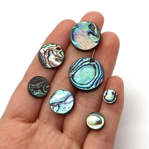 Natural round abalone shell beads for DIY jewelry making held in hand for size