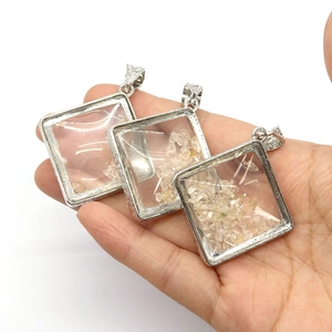 Rhombus glass pendant with white crystal shards in silver frame held by hand