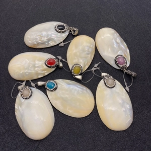 Detalle de colgantes de nácar natural con piedras de colores y circonitas incrustadas
