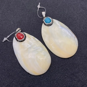Detalle de colgantes de nácar natural con incrustaciones de piedras rojas y azules