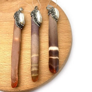 Three brown shell agate bar pendants with pearl and rhinestone inlay on wood tray