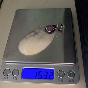 Vista macro de la medida de peso de 15,32g del colgante de concha rosa en báscula