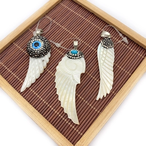 Three natural shell wing pendants with rhinestones on a bamboo display stand
