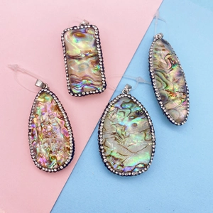 Vue détaillée de divers pendentifs en nacre d'abalone avec bordure en cristal