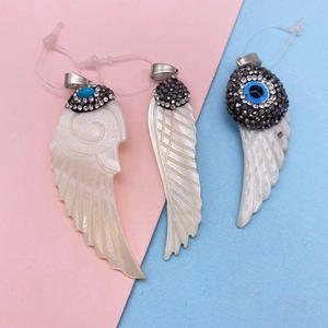 Macro shot of natural shell wing pendants with evil eye inlay and crystals