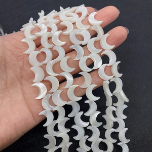 Makroaufnahme von mondförmigen weißen Perlmuttperlen mit natürlichem Glanz für DIY-Schmuck