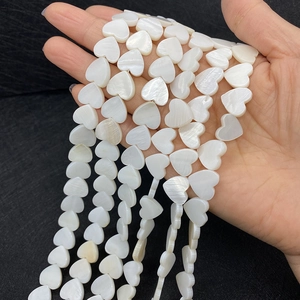 Detalle macro de cuentas de nácar natural blanco en forma de corazón con acabado brillante