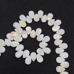 Makro-Detail von birnenförmigen weißen Muschelperlen mit natürlichem Perlglanz für DIY-Schmuck
