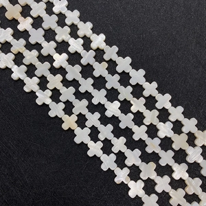 Macro detail of natural white mother of pearl cross shaped beads with iridescent luster