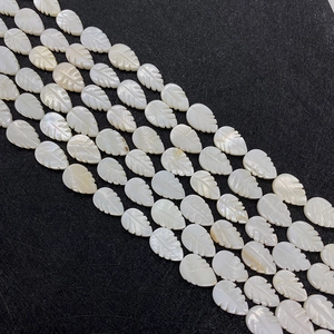 Macro view of hand-carved white mother of pearl shell leaf-shaped beads for DIY jewelry