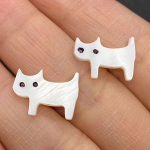Vista macro di perle a forma di gatto in madreperla con finitura iridescente e occhi viola