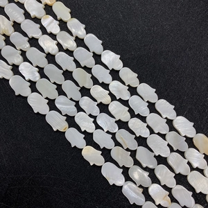 Macro view of iridescent Hamsa hand shaped natural mother of pearl shell beads for DIY jewelry