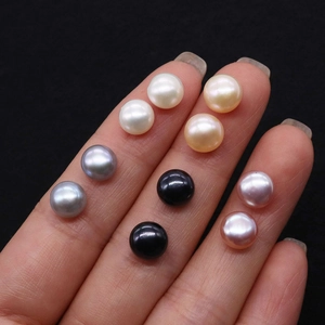 Macro detail of button-shaped freshwater pearls in five colors shown on fingers
