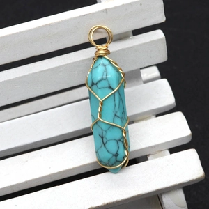Macro shot of turquoise hexagonal prism pendant with gold wire wrapping details
