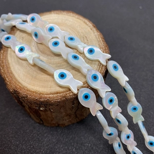 Détail macro de perles de poisson en nacre avec charmes mauvais œil pour bijoux DIY