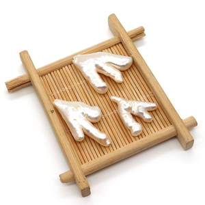 Three baroque freshwater pearls in organic antler shapes displayed on a bamboo tray