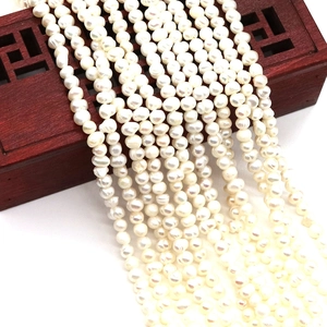 Natural white freshwater pearl strands for DIY jewelry making displayed on a wooden box