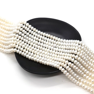 Fili di perle d'acqua dolce bianche naturali su piatto in ceramica nera per gioielli
