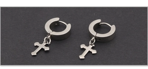 Macro detail of minimalist punk style silver cross earrings on a textured grey background
