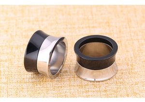 Close-up of dual-tone hip-hop ear tunnels in polished black and silver stainless steel